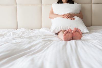 ベッドの上で枕を抱いている女性